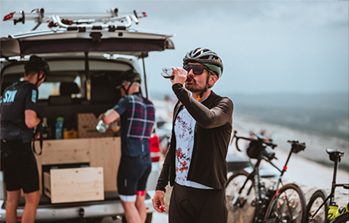 Man wearing ILEVE DISTRICT sports glasses refreshes himself at the top of Mont Ventoux after the climb